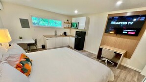 A hotel room with a bed, a desk, a refrigerator, a TV, and a window.