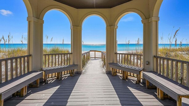 Una passerella in legno coperta con panchine, che conduce a una spiaggia.