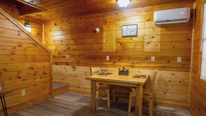 Un interior de madera con una mesa de comedor, sillas, un aire acondicionado de pared y una escalera.