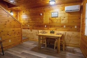 Ein Holzinterieur mit Esstisch, Stühlen, einer Wandklimaanlage und einer Treppe.