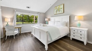 Un dormitorio con una cama grande, un escritorio, una silla, una mesita de noche y una ventana con cortinas.