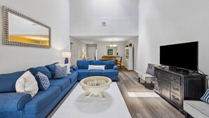 Una sala de estar con un sofá azul, una mesa de centro, un televisor y un aparador.