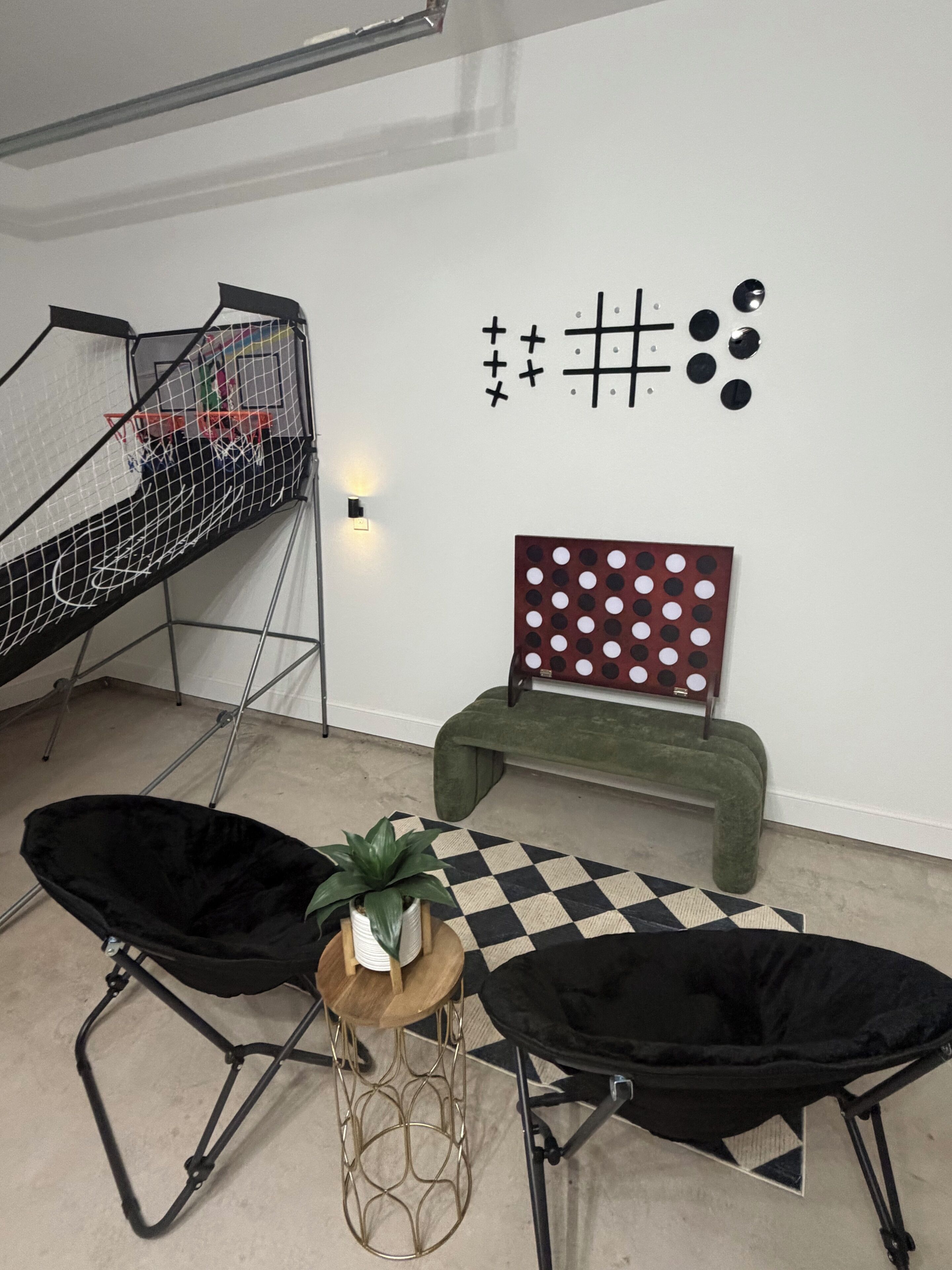 Una habitación con una cama nido, un banco verde, un tapete de cuadros y una decoración en la pared.