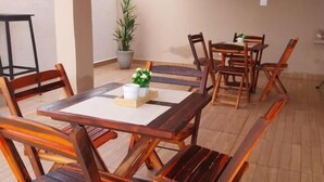 Un coin repas avec une table et des chaises en bois, une plante en pot et un luminaire suspendu.