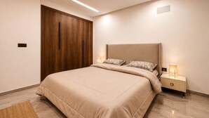Une chambre à coucher comprenant un lit, des tables de chevet, une armoire en bois et un éclairage encastré au plafond.