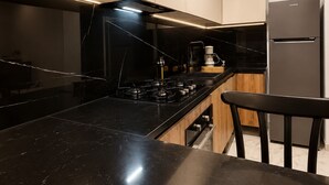 Une cuisine moderne avec des plans de travail noirs, des appareils en acier inoxydable et des armoires en bois.