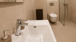 Une salle de bain moderne avec une grande baignoire, des toilettes et une douche à l’italienne.