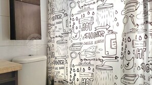Une salle de bain avec un lavabo blanc, un miroir et un rideau de douche orné de motifs enfantins.