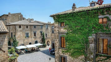 A courtyard with stone buildings, outdoor seating, and a clear sky.