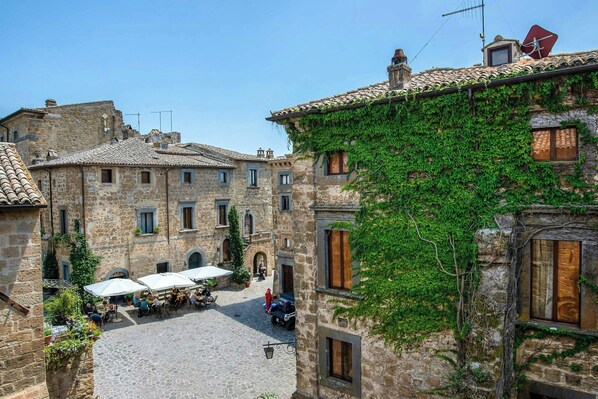 A courtyard with stone buildings, outdoor seating, and a clear sky.