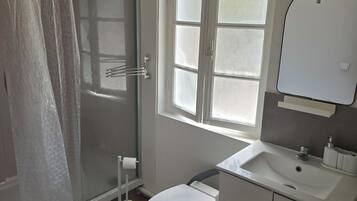 Ein Badezimmer mit Dusche, Toilette, Waschbecken und Fenster.