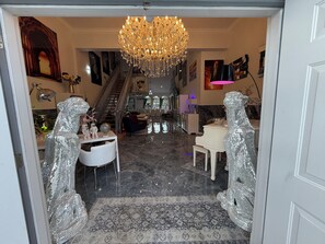 A luxurious interior with a grand chandelier, a piano, and two mirrored sculptures. - Luxury 6 Bedroom Pool Home, Sleeps 14, Water Access and Kayaks (Wilton Manors)