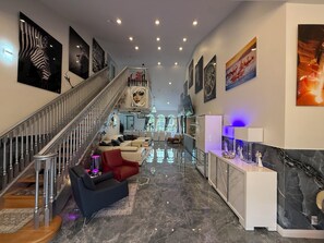 A spacious lobby with a marble floor, a staircase, and various artworks on the walls. - Luxury 6 Bedroom Pool Home, Sleeps 14, Water Access and Kayaks (Wilton Manors)