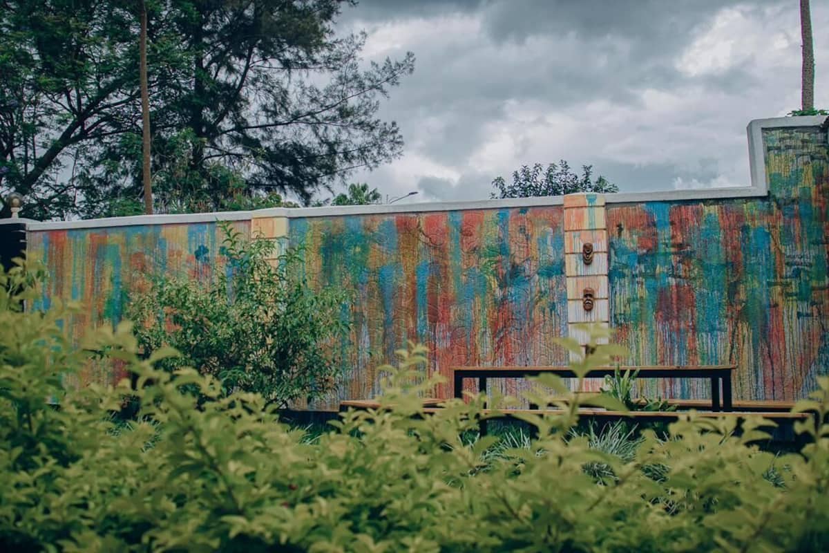 A building with a colorful exterior wall, a bench, and some greenery in the foreground.