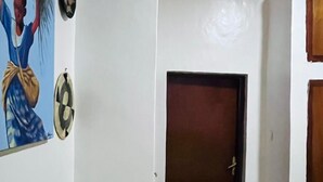 Un pasillo con una puerta cerrada, un reloj en la pared y un picaporte.