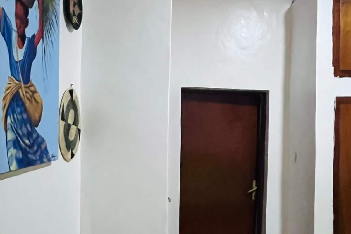 A hallway with a closed door, a wall-mounted clock, and a door handle.