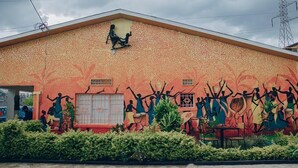 Un edificio con un mural que muestra a personas tocando la batería y bailando.