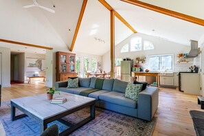 A spacious living area with a large sofa, a coffee table, and a dining area with a table and chairs.