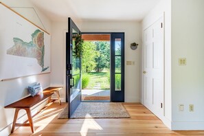 A hallway with a wooden bench, a rug, and a door leading to a garden.