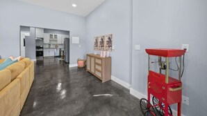 Una sala de estar moderna con un sofá, una cocina al fondo y un carrito rojo con una bicicleta.
