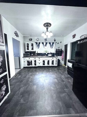 A kitchen with a central island, white cabinets, a black refrigerator, and a chandelier.