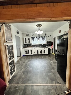 A kitchen with wooden cabinets, a black refrigerator, and a chandelier.