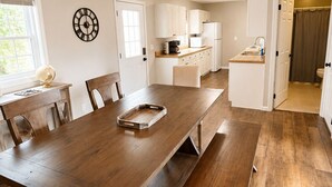 A modern kitchen with a large wooden table, white cabinets, and a globe on the counter. - Caney Overlook Lake Views •Game Room • Minutes to Boat Ramps & Marina (Russell Springs)