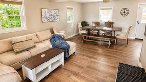A living room with a sofa, coffee table, dining table with benches, and a clock on the wall. - Caney Overlook Lake Views •Game Room • Minutes to Boat Ramps & Marina (Russell Springs)
