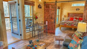 A cozy cabin interior with a dining area, a sofa, and a bed. - Level 2 EV charger~Quiet~clean~cozy~fast WIFI~Dollywood~fireplace~hotub #11 (Sevierville)