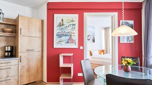A modern kitchen with wooden cabinets, a glass dining table, and a hanging light fixture. - Urlaub auf Rugen: Komfortwohnung mit Fitnessraum (Sellin)