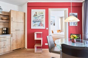 A modern kitchen with wooden cabinets, a glass dining table, and a hanging light fixture. - Urlaub auf Rugen: Komfortwohnung mit Fitnessraum (Sellin)