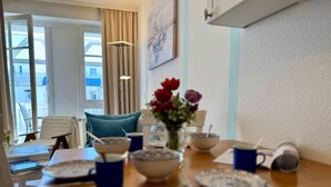 A dining area with a table set for breakfast, a vase with flowers, and a view of the outside. - Gemutliche Ferienwohnung mit Grossem Balkon in Sellin (Sellin)