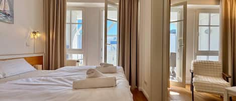 Ein Hotelzimmer mit einem großen Bett, einem Sessel und Blick ins Freie.
