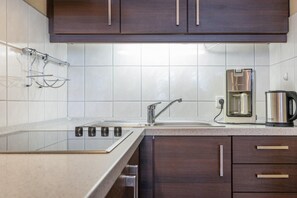 Eine moderne Küche mit Spüle aus Edelstahl, einer Kaffeemaschine und dunklen Holzschränken.