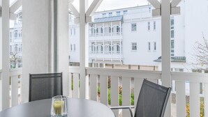 A balcony with white railings, a table with a glass of juice, and a chair. - Attraktive Ferienwohnung fur 4 mit Balkon und Wlan in Sellin (Sellin)