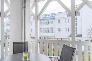 Ein Balkon mit weißen Geländern, einem Tisch mit einem Glas Saft und einem Stuhl.