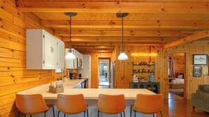 A cabin interior with a kitchen, bar area, and a cozy living space. - The Oak & Oar Camphouse | Family Lake Retreat (Logan)