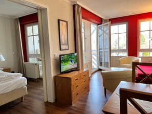 Ein Hotelzimmer mit einem Bett, einem Fernseher auf einer Holzkommode, einem Sessel und einem Tisch.