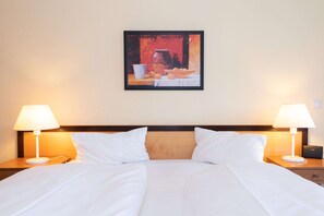 A hotel room with a bed, two bedside lamps, a nightstand, and a painting on the wall. - Attraktive Ferienwohnung fur Vier mit Balkon in Sellin (Sellin)