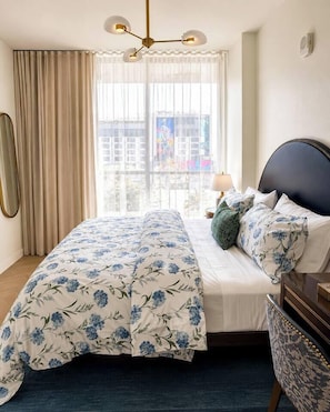 Ein Schlafzimmer mit Bett, Vorhängen, einem Fenster, einer Lampe und einem Nachttisch.