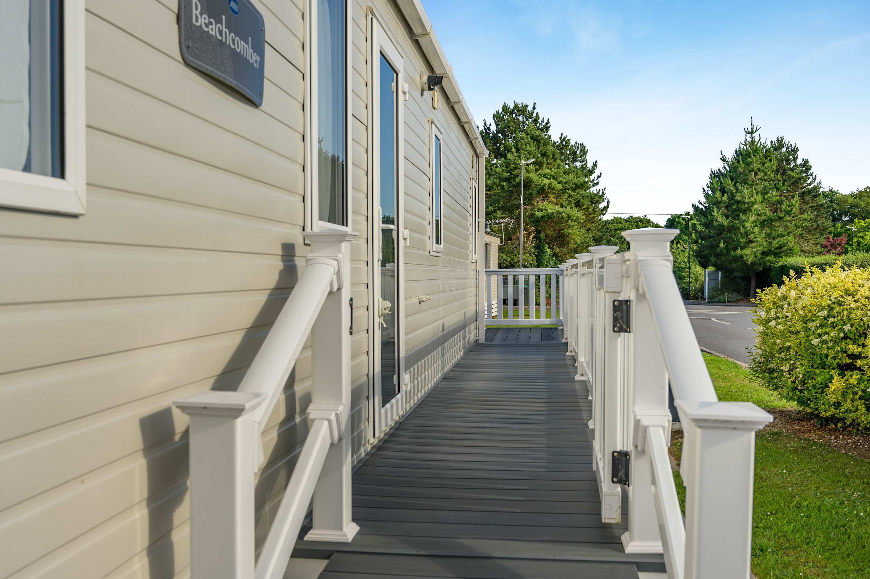 A residential building with a nameplate reading 'Beachcomber,' a covered porch with white railings, and a clear sky in the background.