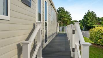 A residential building with a nameplate reading 'Beachcomber,' a covered porch with white railings, and a clear sky in the background.