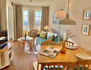 Ein gemütliches Wohnzimmer mit Sofa, Esstisch mit Stühlen, Fernseher und Lampe.