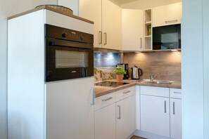 Eine moderne Küche mit weißen Schränken, einem eingebauten Backofen, einer Kaffeemaschine und einem Spülbecken.