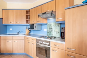 A kitchen with wooden cabinets, a stainless steel oven, a built-in microwave, and a coffee machine. - Ferienwohnung im 1.og mit Balkon in Sellin (Sellin)