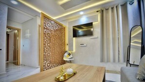 A modern living room with a wooden coffee table, a TV mounted on the wall, and a decorative partition. - Appart moderne -Confort premium près de Guéliz (Marrakech)