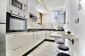 A modern kitchen with white cabinets, a built-in oven, a microwave, and a gas stove. - Appart moderne -Confort premium près de Guéliz (Marrakech)