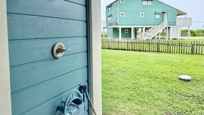 En turkosfärgad byggnad med ett trästaket, en gräsyta och ett litet, runt föremål på marken.