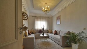 Una sala de estar con sofá, mesa de centro, candelabro y planta en maceta.