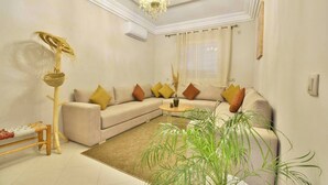 Una sala de estar con un sofá color beige, una mesita redonda y una lámpara de pie.